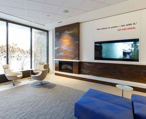 Modern lounge with seating, fireplace, video screen and quote from Jay on the wall