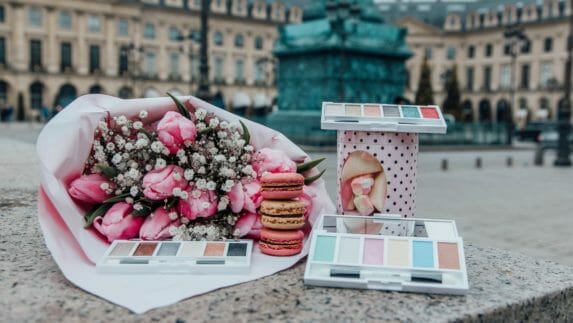 Artistry Studio Parisian Style Edition eye shadow compacts are posed with a bouquet of roses and baby's breath, a stack of macarons and a tin of sweets. Get the effortless "je ne sais quoi" of Parisian girls with our latest collection. Inspired by the style, art, and sweet treats of the City of Lights. Tres chic!