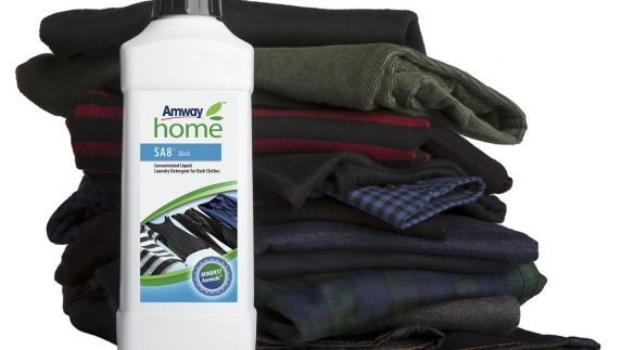 A bottle of SA8 Black Concentrated Liquid Laundry Detergent sits next to a pile of folded dark clothes. SA8 Black Concentrated Liquid Laundry Detergent is specially formulated to keep black and dark-colored fabrics looking newer longer - especially those made of cotton.